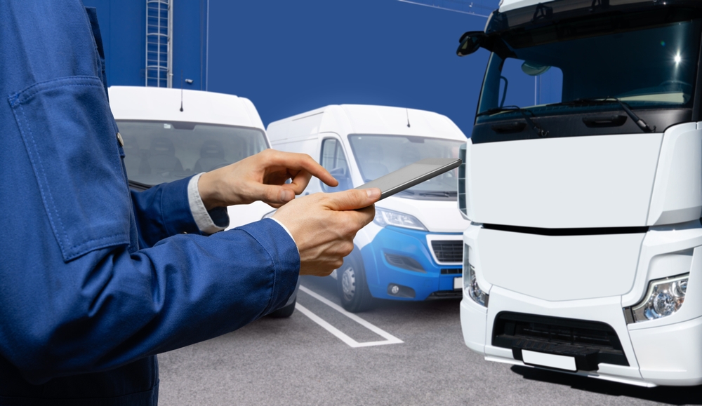 A man is holding a tablet in front of a white truck.